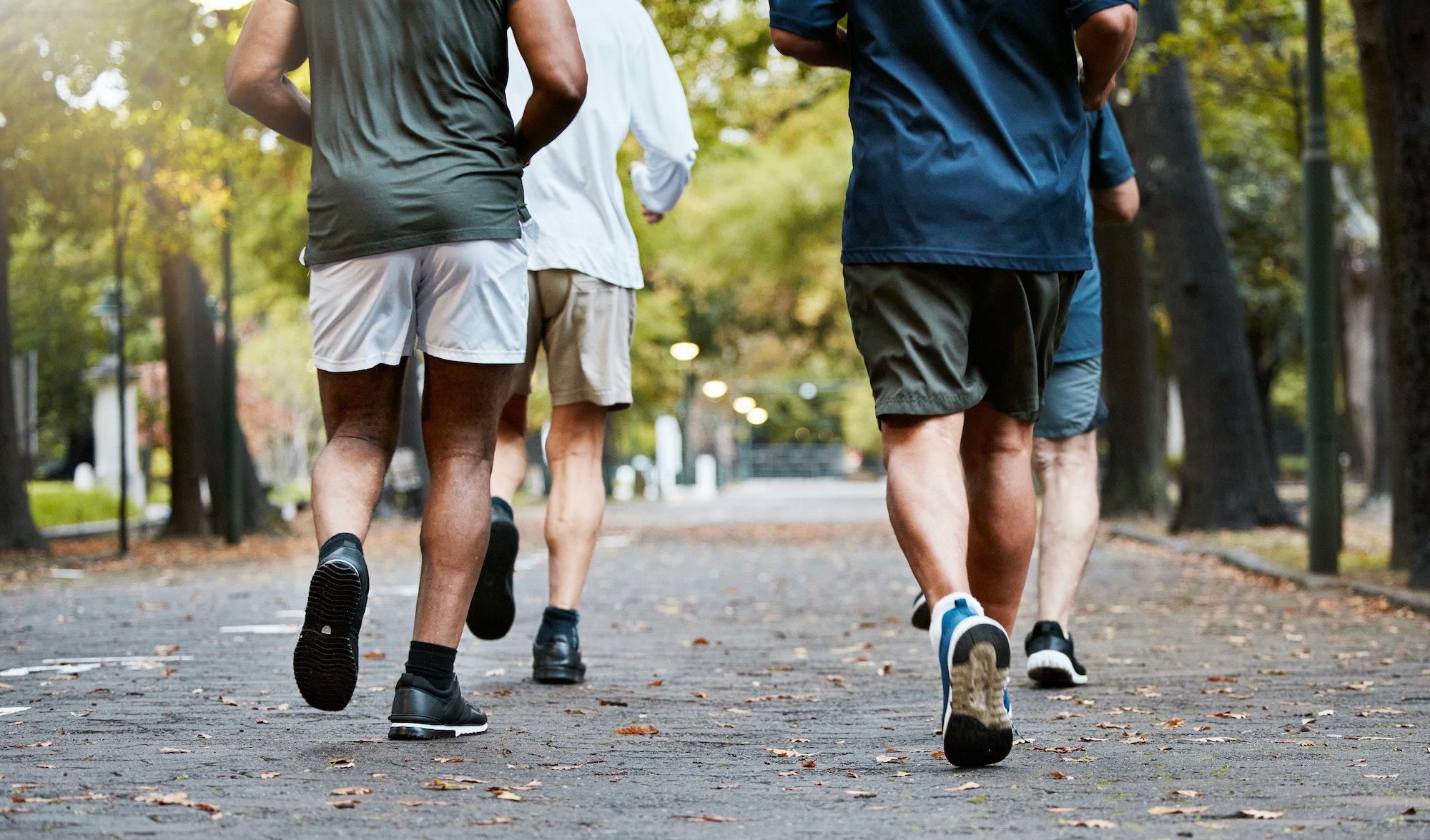 Fitness, men and running club in park, cropped legs in nature for exercise on garden path together.