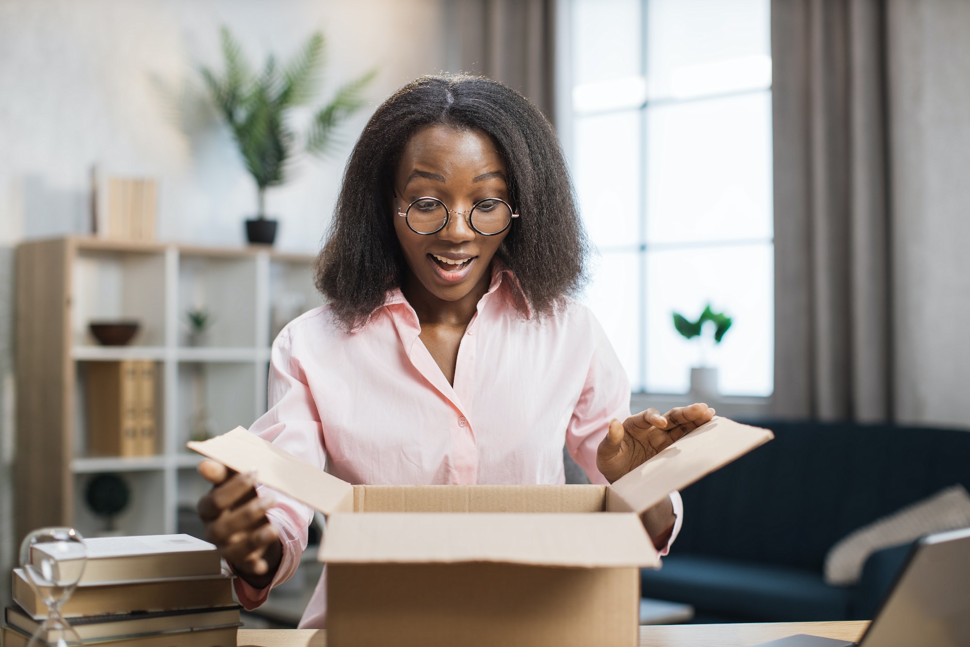 Surprised african woman unpacking parcel box